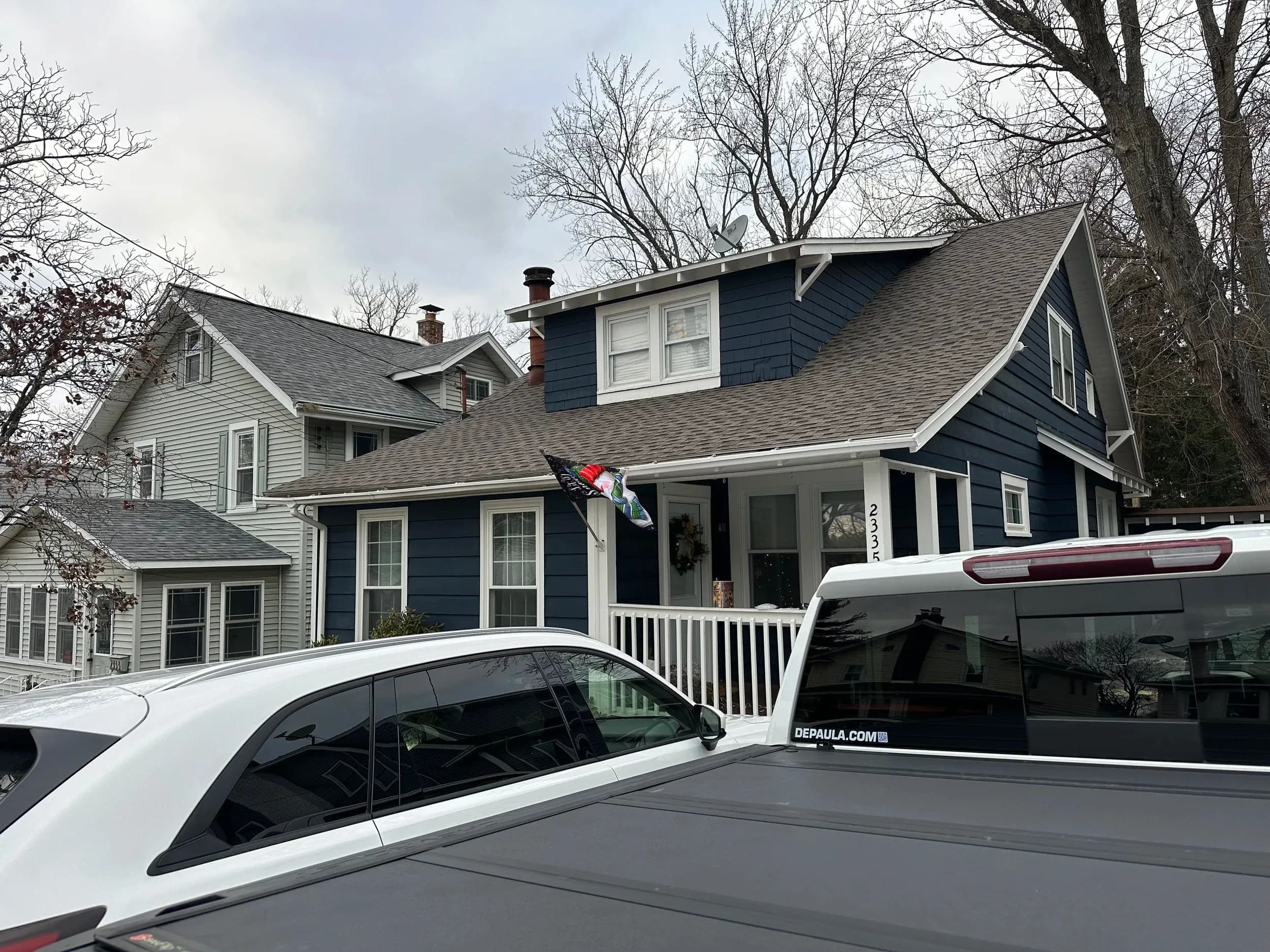 Blue Craftsman House Exterior With Service Trucks Parked