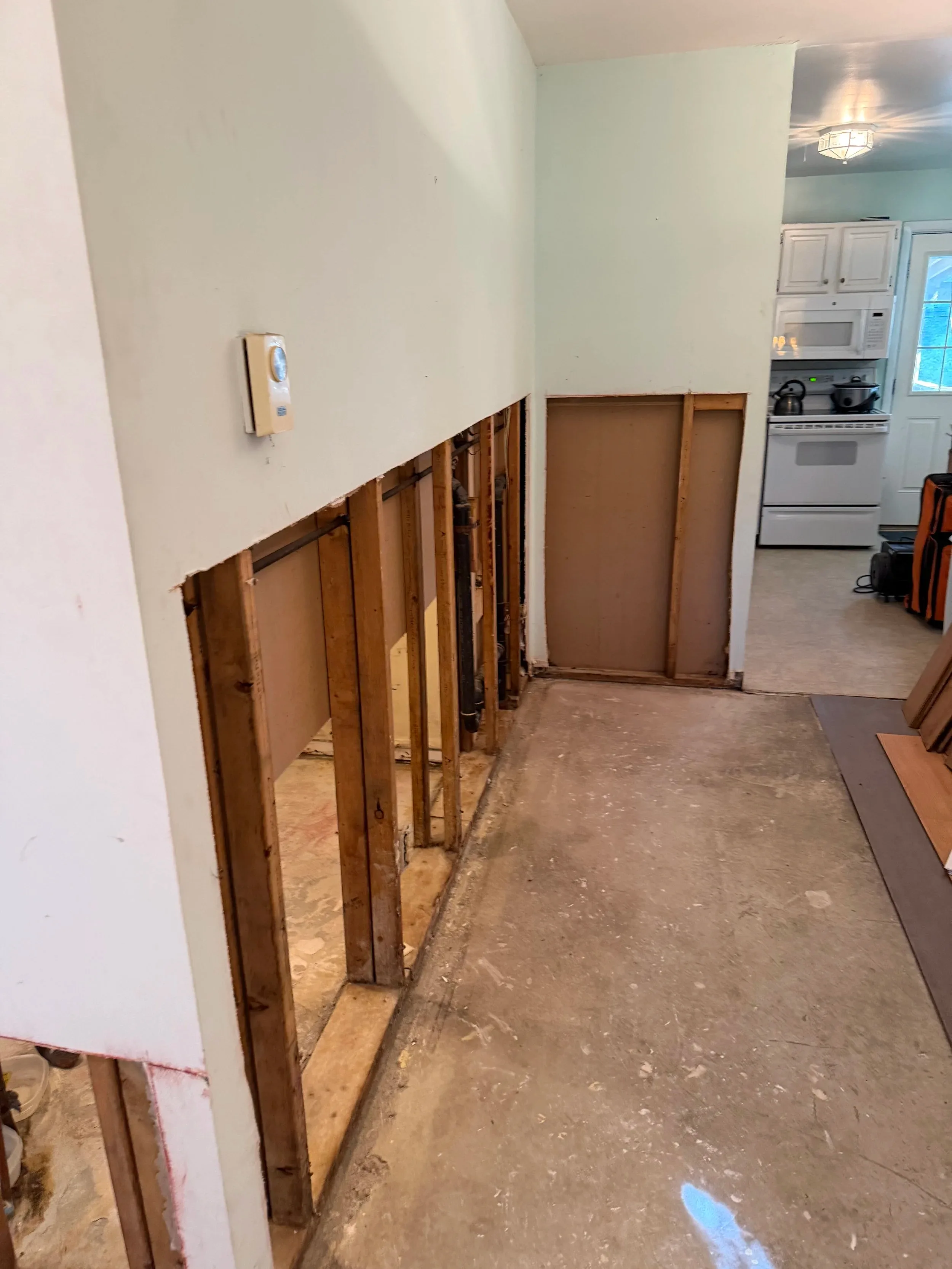 Gutted Hallway Wall Exposed Studs Plumbing Kitchen View