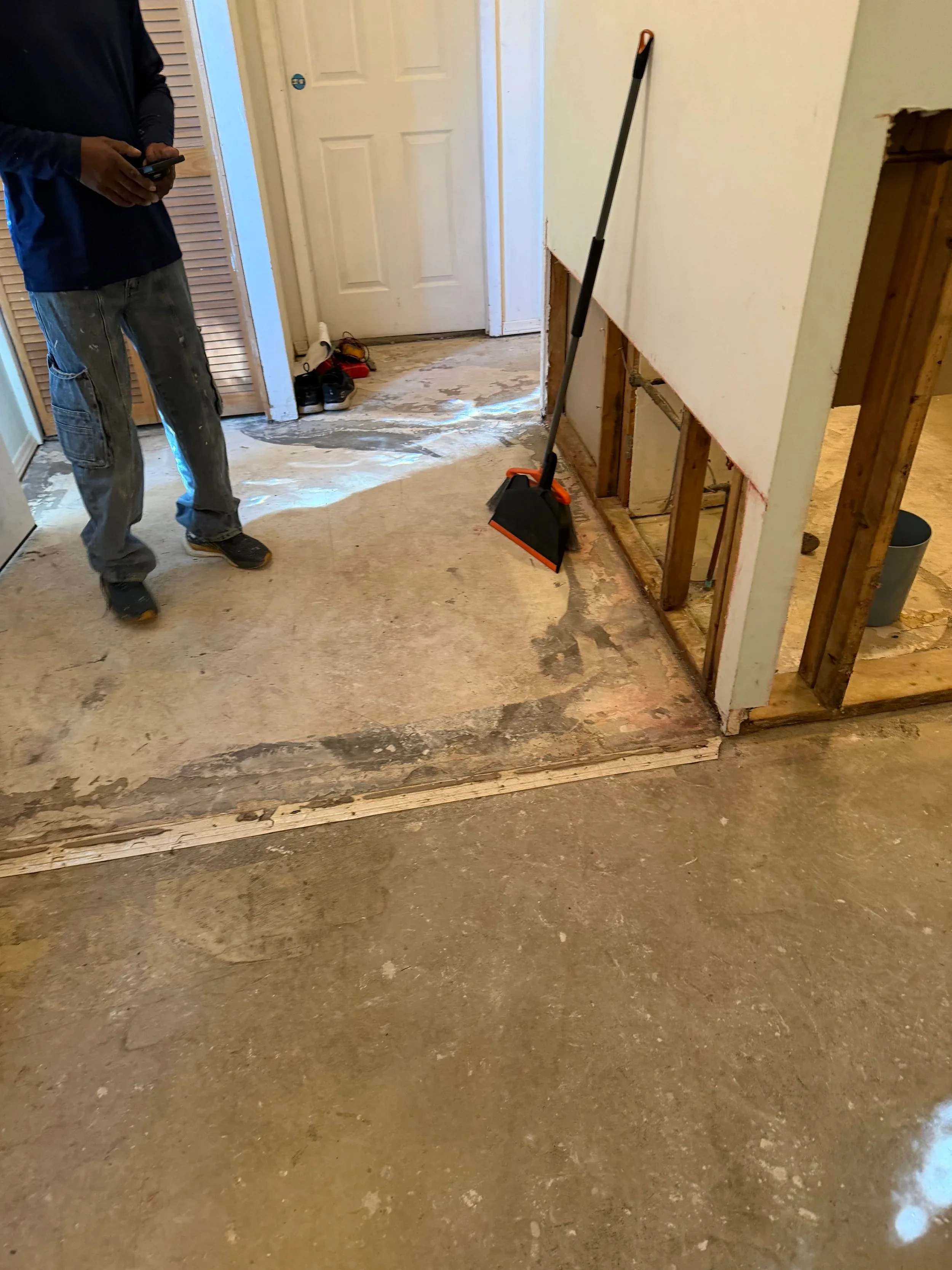 Worker Sweeping Debris Gutted Hallway Renovation