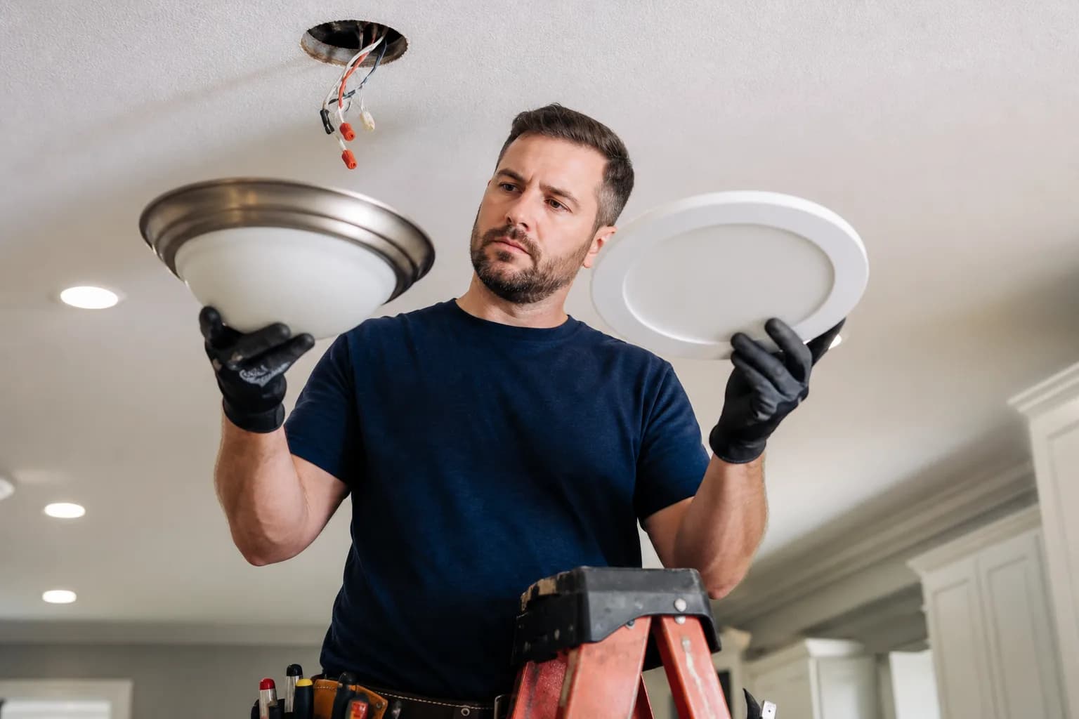 Electrician upgrading a home light fixture to an energy-efficient model