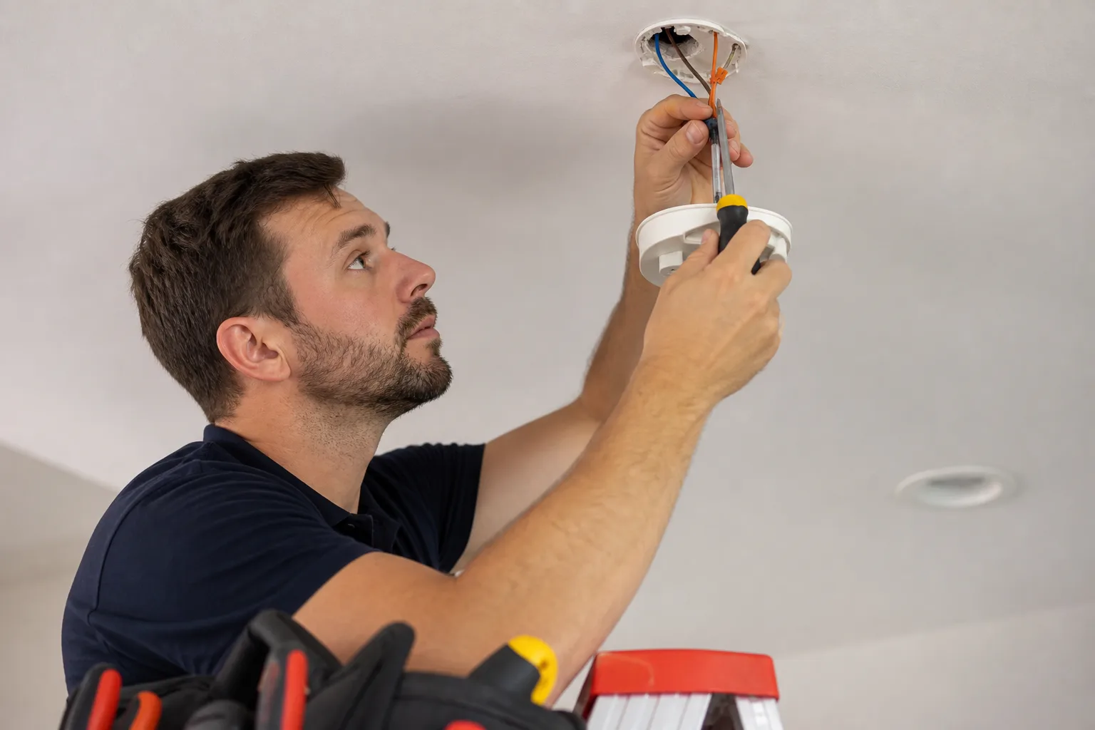 Electrician installing a smoke detector on a home ceiling