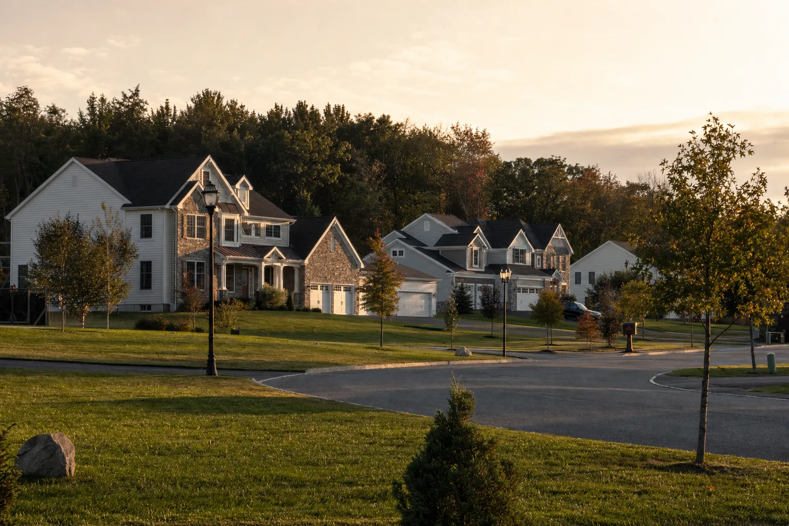 Newer Malta, NY neighborhood of large colonial homes with stone accents and three-car garages at golden hour