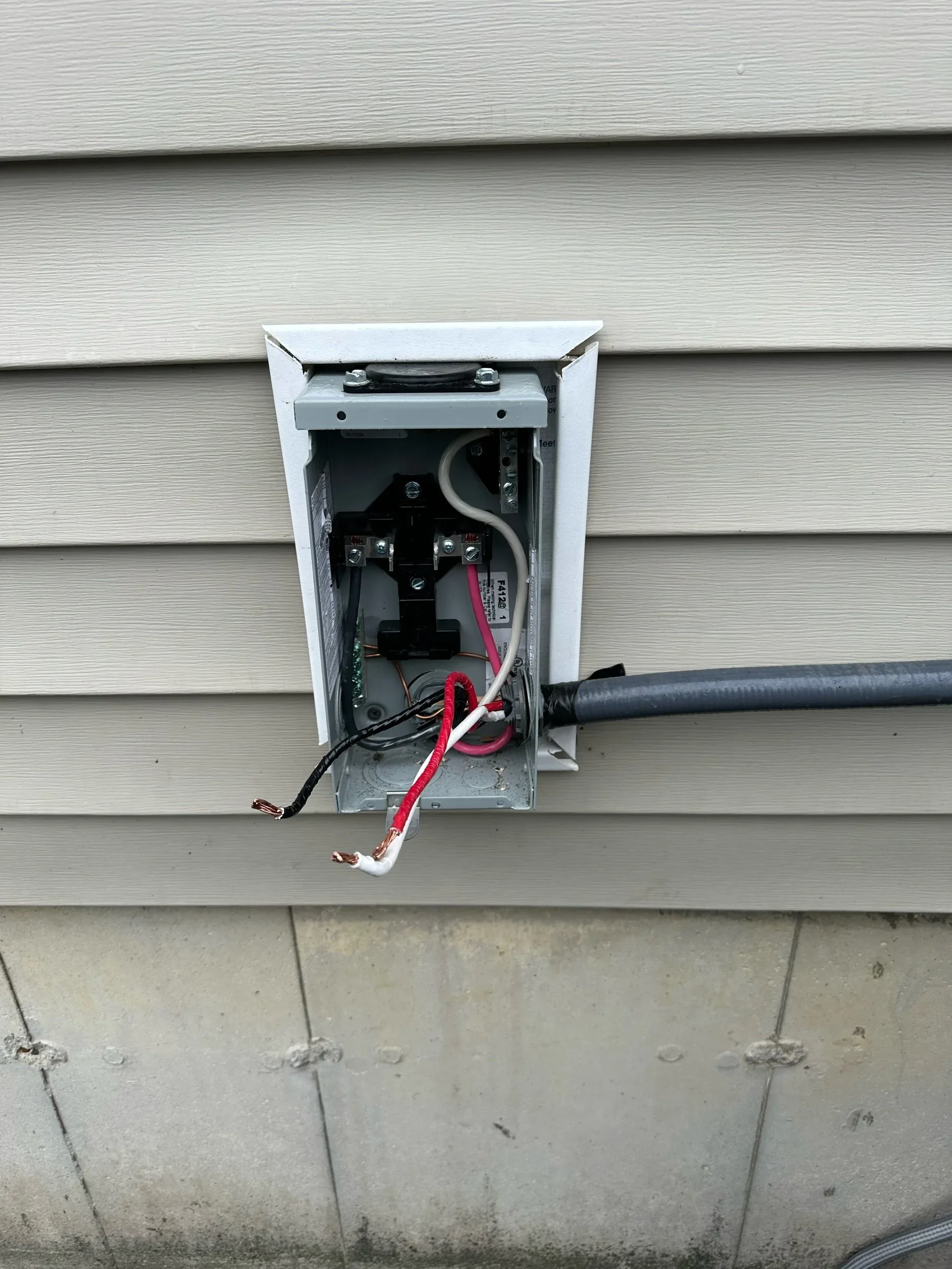 New outdoor electrical meter base installed on vinyl siding