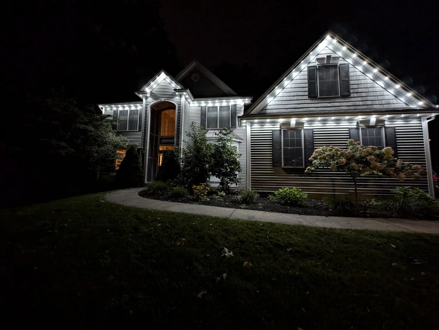 Permanent LED roofline lighting along a white house gable